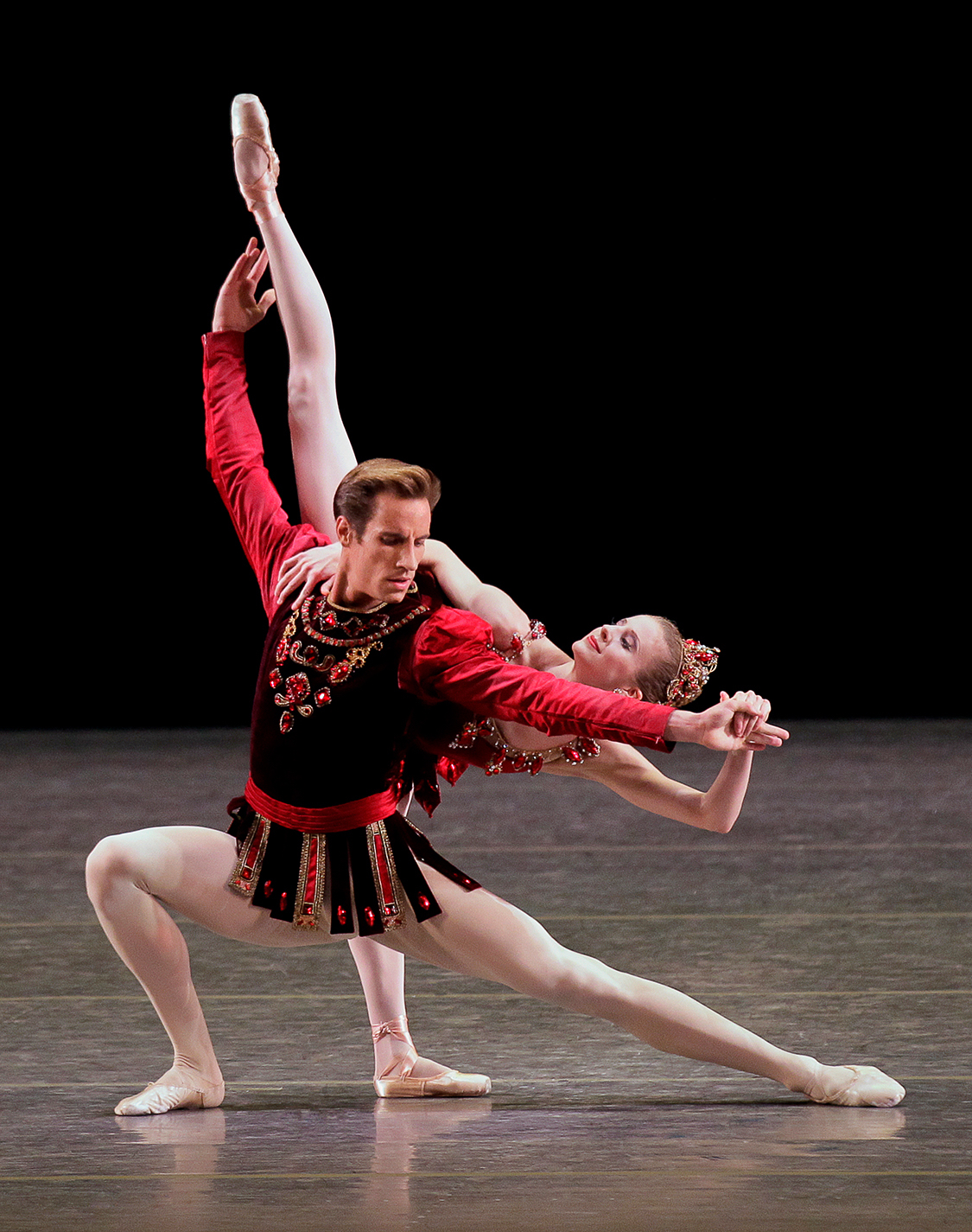 Sterling Hyltin in a six o'clock arabesque behind a kneeling Andrew Veyette
